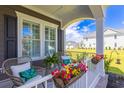 Cozy front porch with wicker seating, decorative pillows, colorful potted flowers, and views of the neighborhood at 966 Crystal Water Way, Myrtle Beach, SC 29579