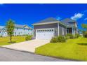 Side view of a gray home featuring a two-car garage and a well-maintained lawn at 966 Crystal Water Way, Myrtle Beach, SC 29579
