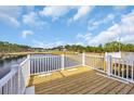 Wooden porch with white railing overlooks community pond and treeline at Tbb Lineback Pl. # 32, Longs, SC 29568