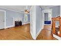 Living room with a white fireplace, hardwood floors, light blue walls, and a ceiling fan at 203 Lakeland Dr., Conway, SC 29526
