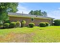 Expansive backyard with lush green grass, mature trees, and brick exterior, perfect for outdoor activities at 324 Camellia Ave., Marion, SC 29571