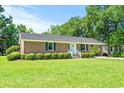 Traditional brick home showcases a spacious lawn and mature trees, offering a serene and picturesque setting at 324 Camellia Ave., Marion, SC 29571