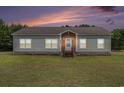 Charming single-story home with vinyl siding, a brick foundation, and well-manicured lawn at sunset at 580 Circle M Rd., Longs, SC 29568