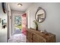 Entryway featuring a decorative cabinet, round mirror, and red front door leading to a landscaped yard at 6570 Pebble Beach Crescent, Myrtle Beach, SC 29588