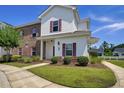 Attractive two-story townhome with red shutters, brick accents, and manicured landscaping on a sunny day at 8855 Radcliff Dr. Nw # 50B, Calabash, NC 28467