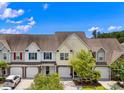 A row of well-maintained townhomes with colorful accents, driveways, and mature trees under a bright sky at 2131 Cass Lake Dr. # 662, Carolina Shores, NC 28467