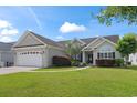 Home exterior featuring a two-car garage, well-maintained lawn, and charming front entrance with mature landscaping at 232 White Water Loop, Conway, SC 29526