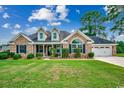 Charming single-story brick home featuring an attached two-car garage and a well-manicured front lawn and garden at 301 Farmtrac Dr., Galivants Ferry, SC 29544