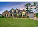 Inviting brick home with well-kept lawn, dormer windows, and an attached garage, all under a beautiful sky at twilight at 301 Farmtrac Dr., Galivants Ferry, SC 29544