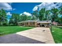 View of a long driveway and basketball hoop leading to the home, surrounded by lush greenery at 4189 Schoolhouse Circle, Little River, SC 29566