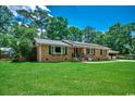Well-maintained brick home with a lush green lawn, windows with black shutters, and solar panels at 4189 Schoolhouse Circle, Little River, SC 29566
