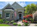 Attractive brick home featuring colorful flower beds, an American flag, and covered entryway at 6400 Longwood Dr., Murrells Inlet, SC 29576