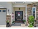 Welcoming front entrance with decorative plants, wreath, and stone accents at 752 Hobonny Loop, Longs, SC 29568