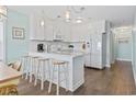 Bright kitchen featuring white cabinets, white appliances, bar seating and wood-look flooring at 4105 S Ocean Blvd. # 102, North Myrtle Beach, SC 29582