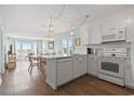 Bright open concept kitchen featuring white appliances and cabinets with an adjacent living room and ocean view at 4105 S Ocean Blvd. # 102, North Myrtle Beach, SC 29582