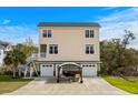 Exterior view of a two-story home featuring a spacious driveway, covered patio, and well-maintained lawn at 4387 Landing Rd., Little River, SC 29566