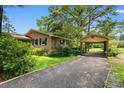A brick home with a car port and a gravel driveway framed by mature trees and landscaping at 1272 Park Hill Dr., Conway, SC 29526