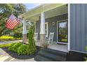 Close-up of the charming front porch featuring rocking chairs and an American flag at 2588 Long Avenue Ext., Conway, SC 29526