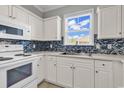 Well-lit kitchen with white appliances, updated backsplash, and a view from the window at 300 Kiskadee Loop # K, Conway, SC 29526