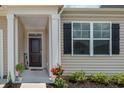 Charming covered entryway with decorative black door, black shutters, and complementary plants at 964 Irving Dr., Little River, SC 29566