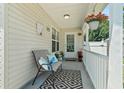 Inviting front porch area with a cozy chair, patterned rug and hanging flower basket at 1007 Autumn Dr., Murrells Inlet, SC 29576