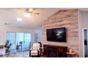 Cozy living room with decorative wood accent wall, mounted TV, ceiling fan, and plenty of natural light at 219 Birdie Way, Longs, SC 29568