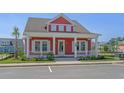 Charming red home features a welcoming front porch, white trim, and manicured landscaping at 8148 Living Tide Dr., Myrtle Beach, SC 29572