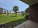 A serene exterior view shows a lush lawn and distant buildings with a clear blue sky at 1514 Lanterns Rest Dr. # 103, Myrtle Beach, SC 29579
