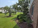 Well-manicured lawn with palm trees and lush bushes adjacent to a brick building at 1514 Lanterns Rest Dr. # 103, Myrtle Beach, SC 29579
