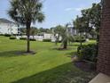 Green lush lawn with palm trees and a fenced pool in the distance on a sunny day at 1514 Lanterns Rest Dr. # 103, Myrtle Beach, SC 29579