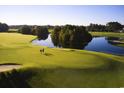 Scenic golf course view with well-manicured green, shimmering lake, and two golfers on a beautiful afternoon at 223 Atlantic Breeze St., Myrtle Beach, SC 29572
