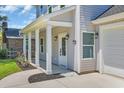 Close-up of the home's entrance showcasing a covered porch, stylish lighting, and landscaping at 4329 Landing Rd., Little River, SC 29566