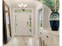 Bright foyer featuring wood floors, decorative mirror, light fixture, and white front door at 5087 Sundrop Ln., Little River, SC 29566