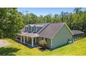 Exterior showcasing the covered porch, screened-in pool area and lush lawn on a sunny day at 140 Pixie Dust Ct., Myrtle Beach, SC 29588
