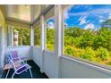 Screened-in porch/balcony overlooking lush greenery and a clear blue sky with comfortable seating at 1450 St. George Ln. # E, Myrtle Beach, SC 29588