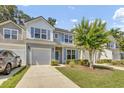 Charming two-story home featuring a garage, blue shutters, and a well-manicured lawn with a beautiful flowering tree at 315 Bulkhead Bend # 315, Carolina Shores, NC 28467