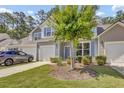 Charming two-story home featuring a garage, blue shutters, and a well-manicured lawn with a beautiful flowering tree at 315 Bulkhead Bend # 315, Carolina Shores, NC 28467