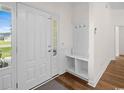 Bright entryway with tile flooring, a storage bench, coat hooks, and natural light streaming through the front door at 409 Cypress View Ave., Little River, SC 29566