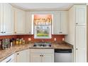 Bright kitchen with white cabinets, stainless sink, and a large window offering a view of the backyard at 943 Oak St., Aynor, SC 29511
