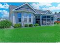 Beautiful backyard featuring lush green grass, mature landscaping, and a screened-in porch at 35 Palmetto Green Dr., Longs, SC 29568