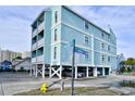 Exterior perspective of a teal building with parking underneath the raised structure at a street intersection at 200 S Ocean Blvd. # 3-B, North Myrtle Beach, SC 29582