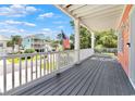 A spacious porch featuring a gray wood floor, white railings, and views of a charming street at 3304 Palm St., North Myrtle Beach, SC 29582