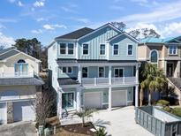 Stunning light blue three-story home with white trim, a two-car garage, and charming balcony at 112 Waterway Crossing Ct., Little River, SC 29566