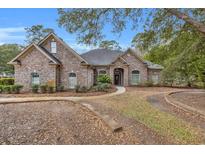 Charming brick home with arched windows, a manicured lawn, and mature trees creating curb appeal at 1262 Limestone St., Murrells Inlet, SC 29576