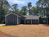 Newly built home with gray siding, red door and landscaped lawn at 9 Gumwood Dr., Carolina Shores, NC 28467