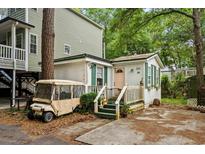 Charming villa with green trim, a golf cart, and mature trees at 6001 - Villa 2 S Kings Hwy., Myrtle Beach, SC 29575