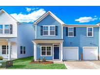 Two-story light blue home with white garage door and landscaping at 718 Nw Palm Frond Way # 66, Calabash, NC 28467