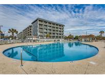 Enjoy this spacious outdoor swimming pool with an ocean view, lounge chairs, and beautiful gray condo building at 5905 S Kings Hwy. # A 115, Myrtle Beach, SC 29575