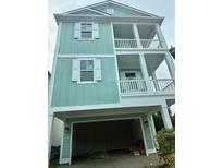 Inviting three-story home with an open garage, mint green siding, and double-decker balconies at 1207 Salt Windy Way, North Myrtle Beach, SC 29582