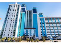 A multi-story white and blue resort-style condo building with palm trees at its entrance at 3000 N Ocean Blvd. # 420, Myrtle Beach, SC 29577